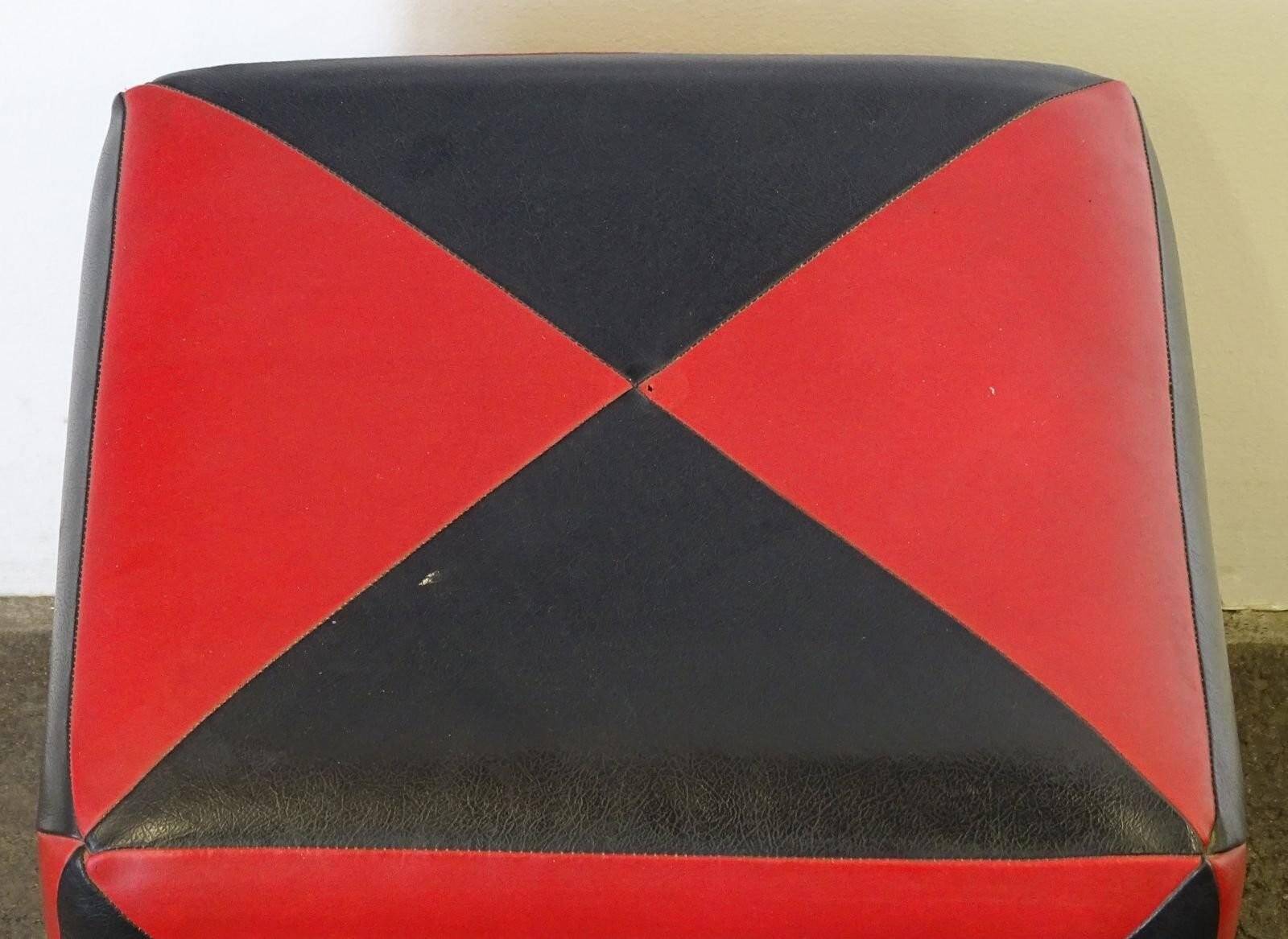 Mid-century ottoman stool in red and black faux leather with wooden legs.