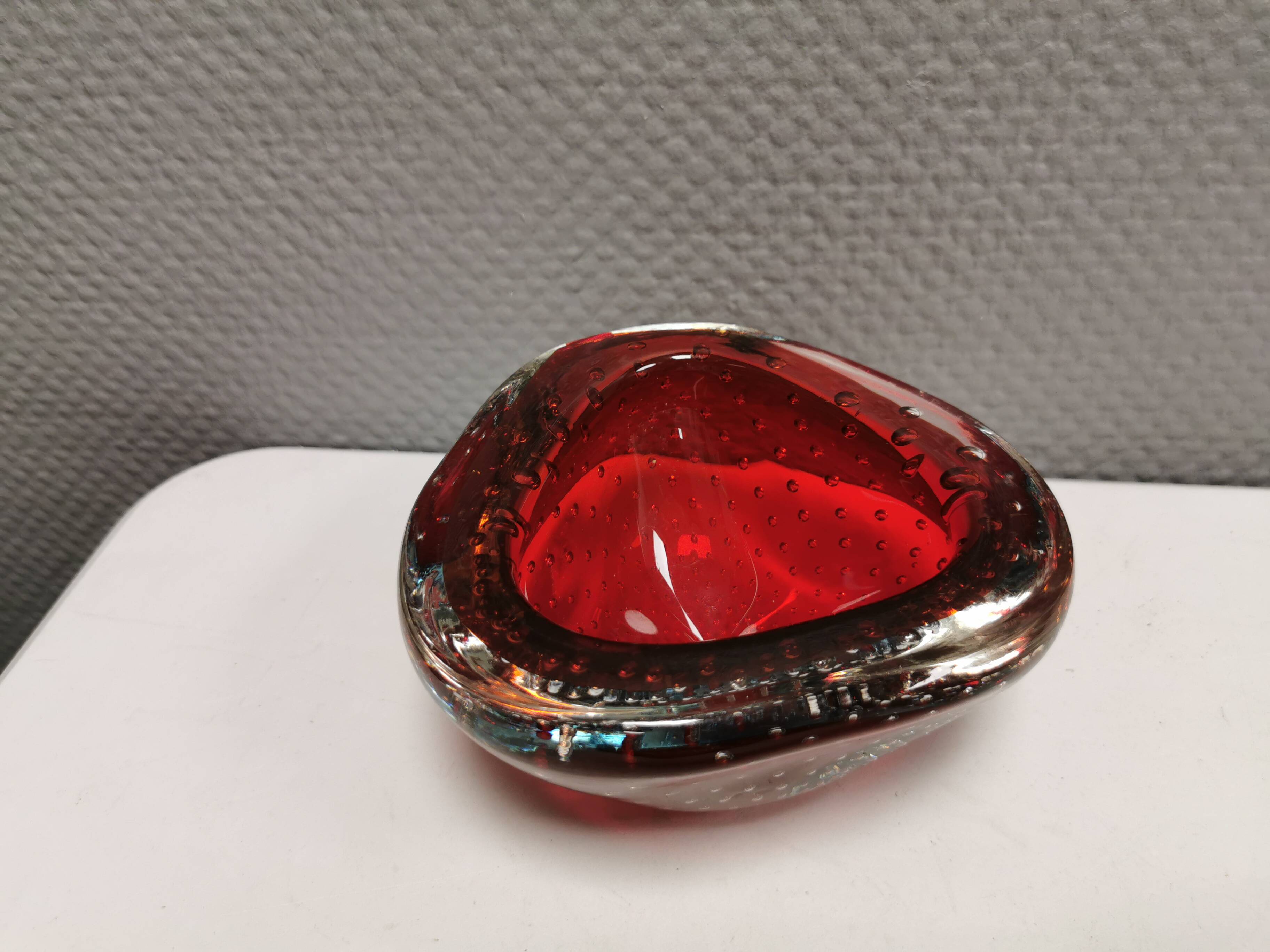 Small glass bowl in beautiful emerald red color with inlaid bubbles.