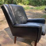 Mid-Century Italian armchair from the 1960s in black leather and dark wood, with a tufted backrest.