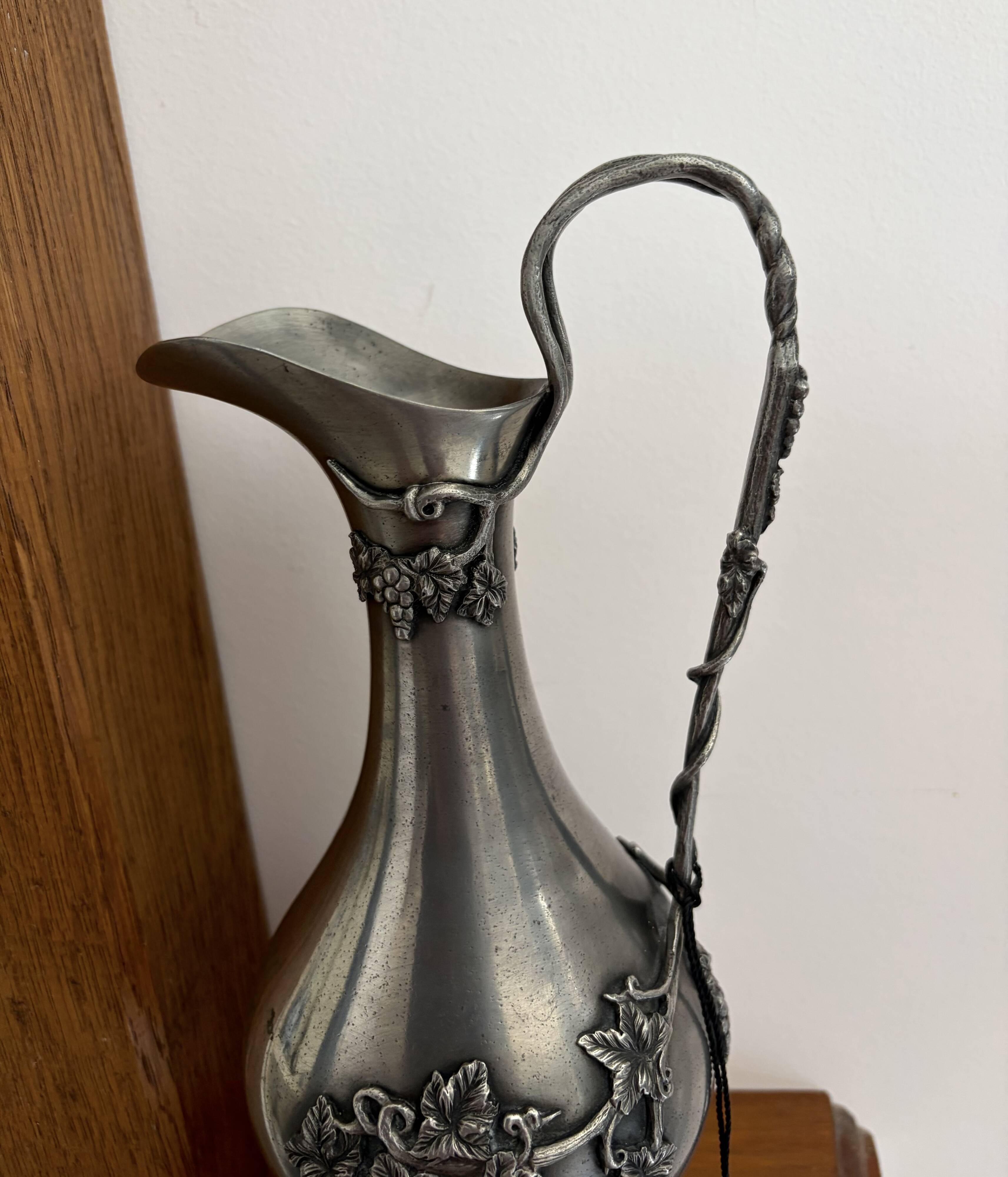 Ewer in pewter surrounded by vine branches with g