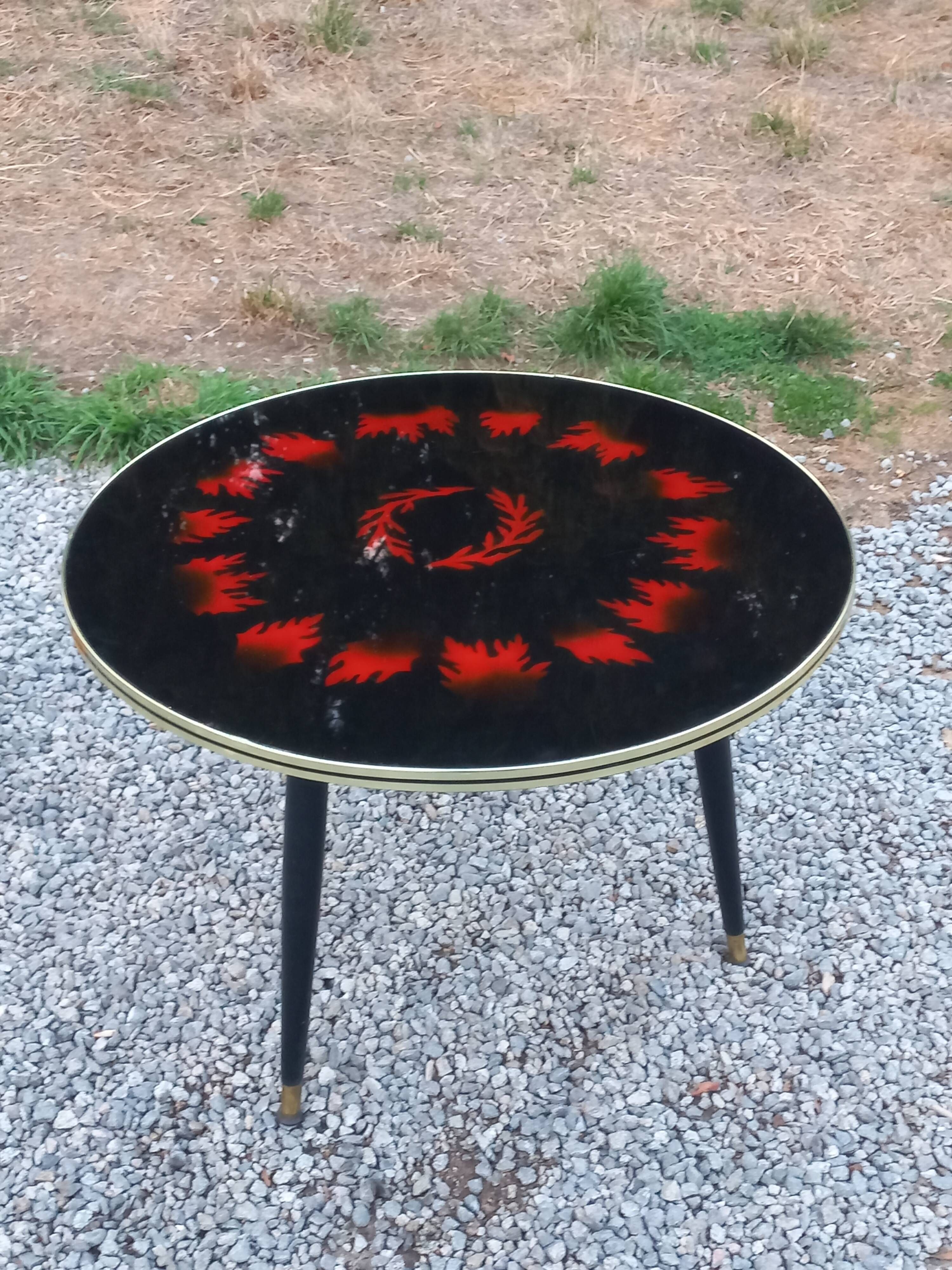 Vintage coffee table with glass top and tripod legs in blackened wood from the 1960s.