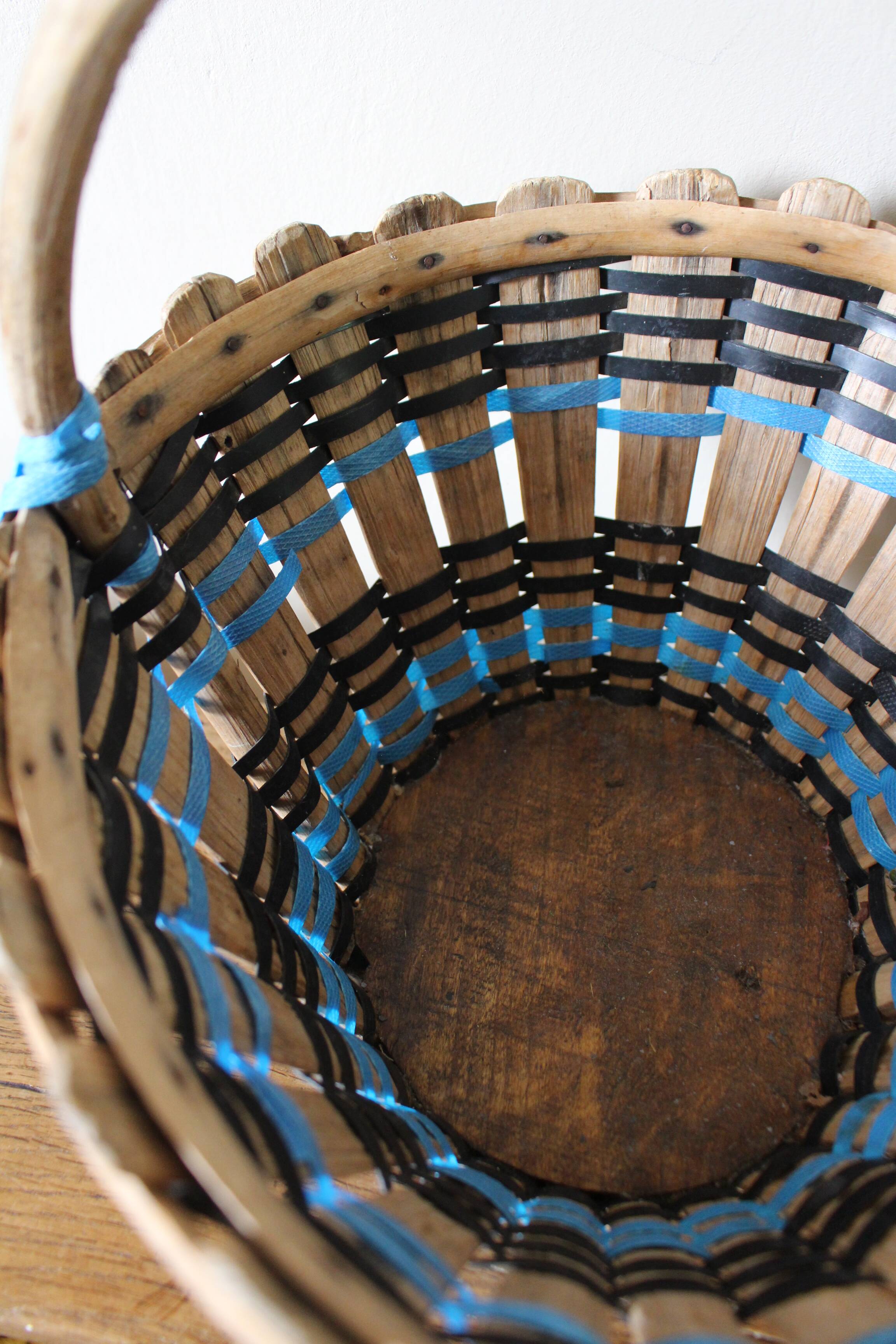 Vintage wooden basket with round handle, blue and black weaving.