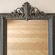 Antique mirror with a sculpted pediment in classic grey style.