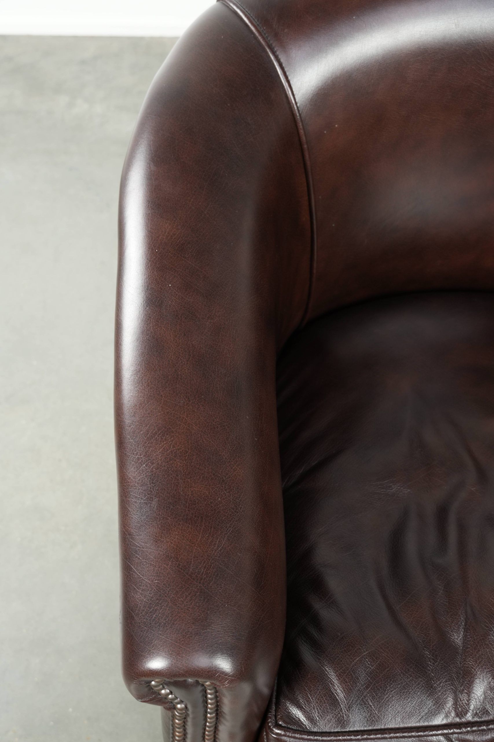 Dark cow leather club armchair with a stylish design in English style