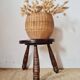Small brutalist tripod stool made of turned wood.