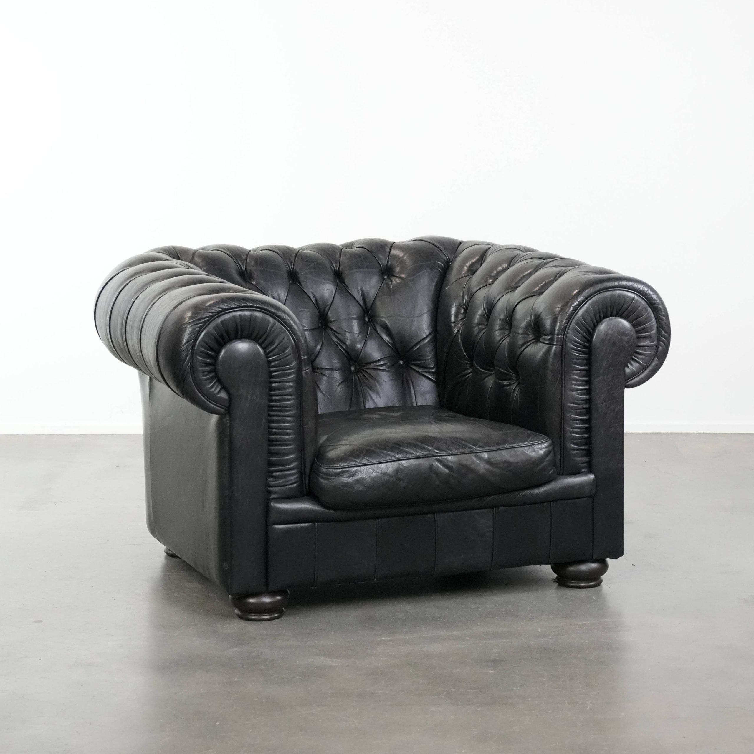 Comfortable black chesterfield armchair made of cowhide leather