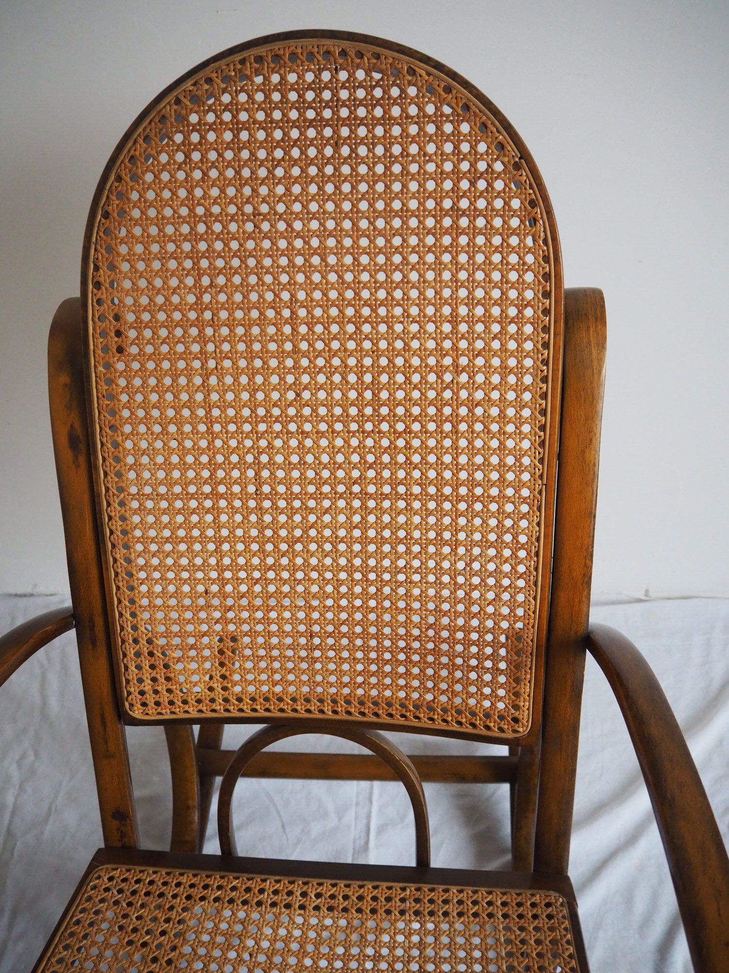 Rocking-chair en bois teinté et assise cannée
