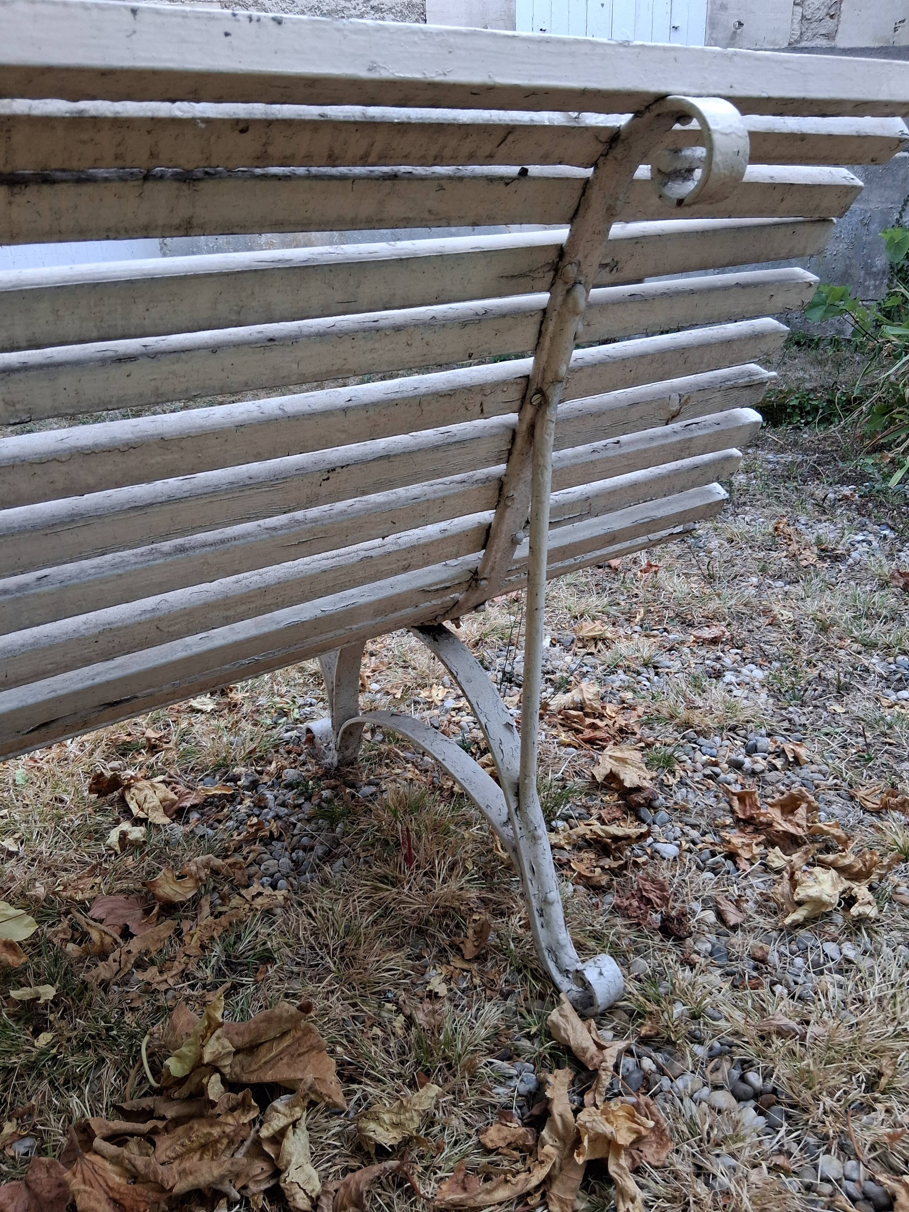 Pair of antique wooden slatted benches with wrought iron legs.