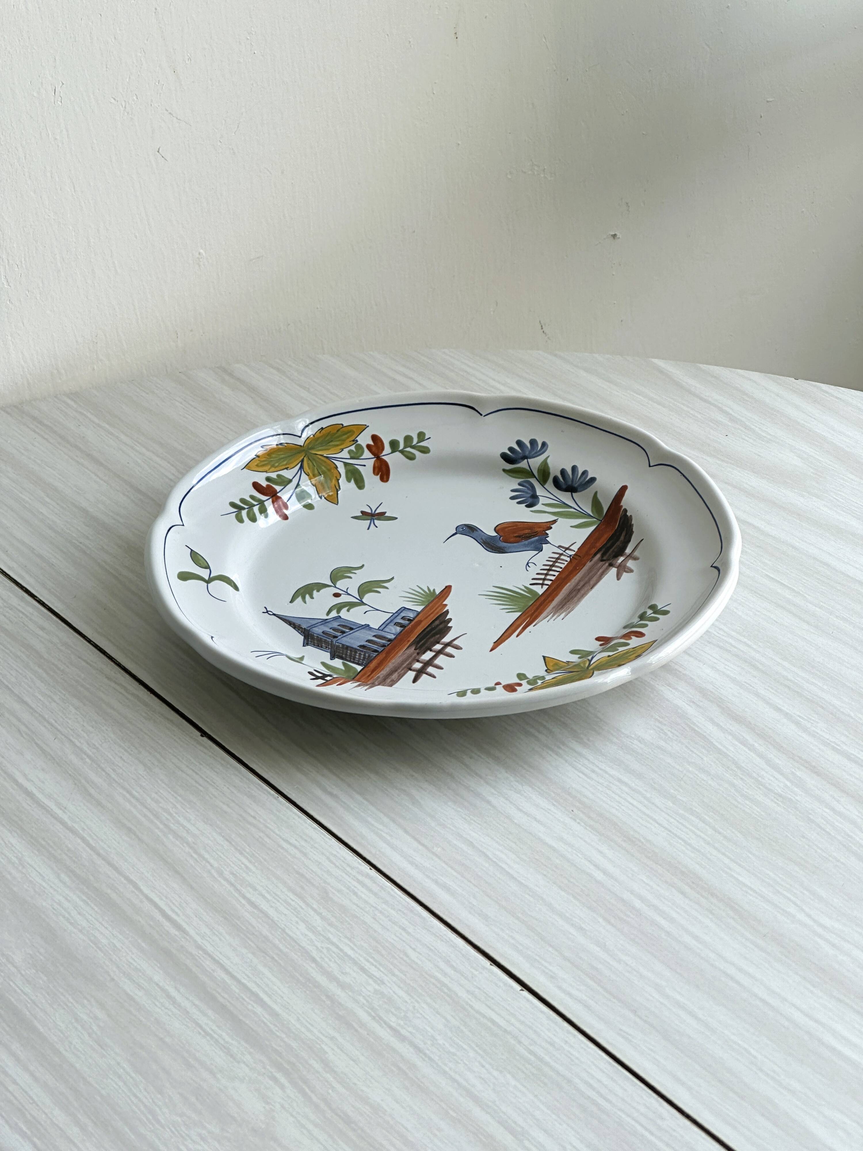 Hand-painted earthenware plate with landscape and bird decoration.