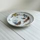 Hand-painted earthenware plate with landscape and bird decoration.