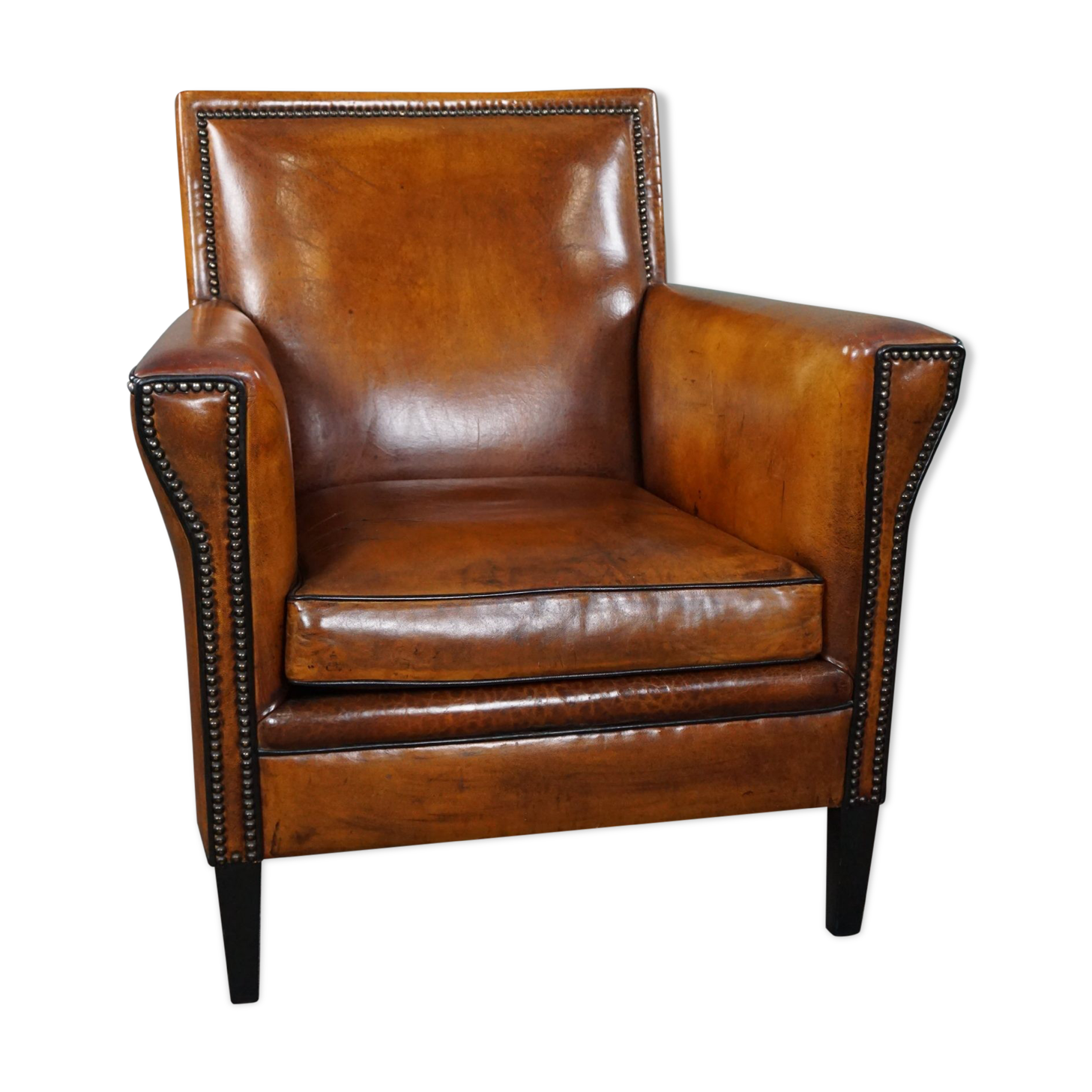 Art deco armchair in sheepskin with black piping and decorative nails