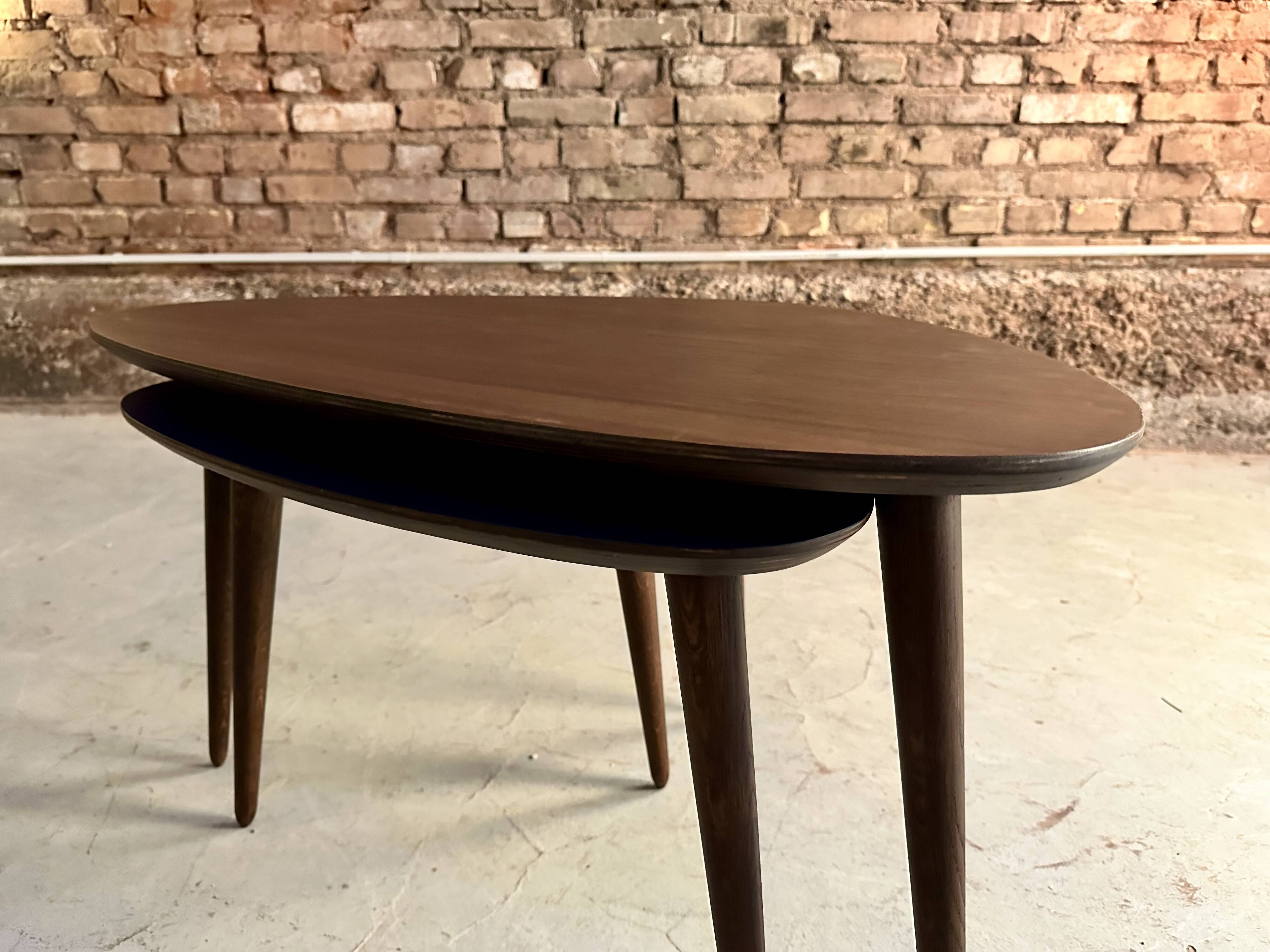 A pair of tripod and nesting coffee tables in walnut and midnight blue.