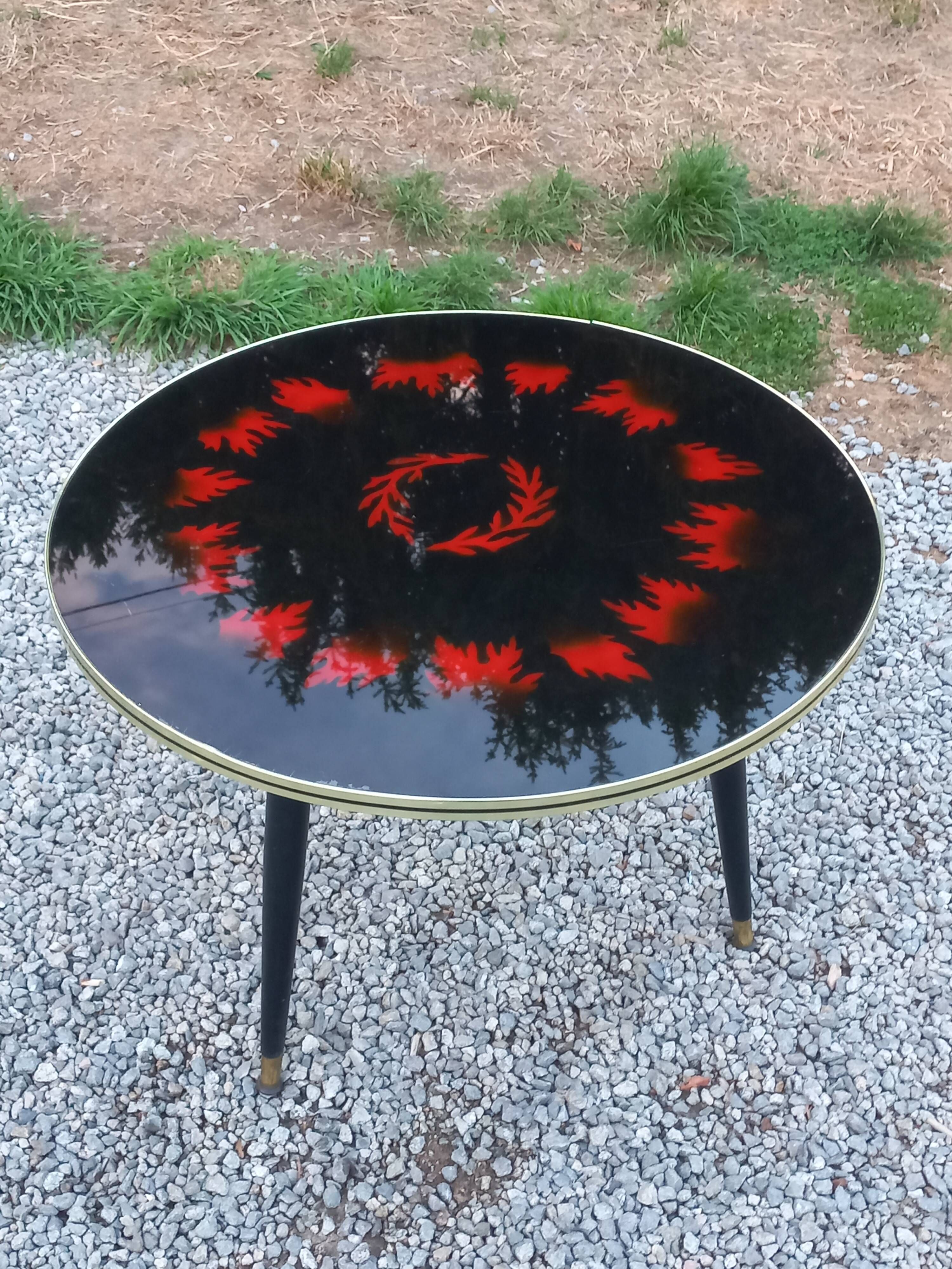 Vintage coffee table with glass top and tripod legs in blackened wood from the 1960s.