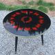 Vintage coffee table with glass top and tripod legs in blackened wood from the 1960s.