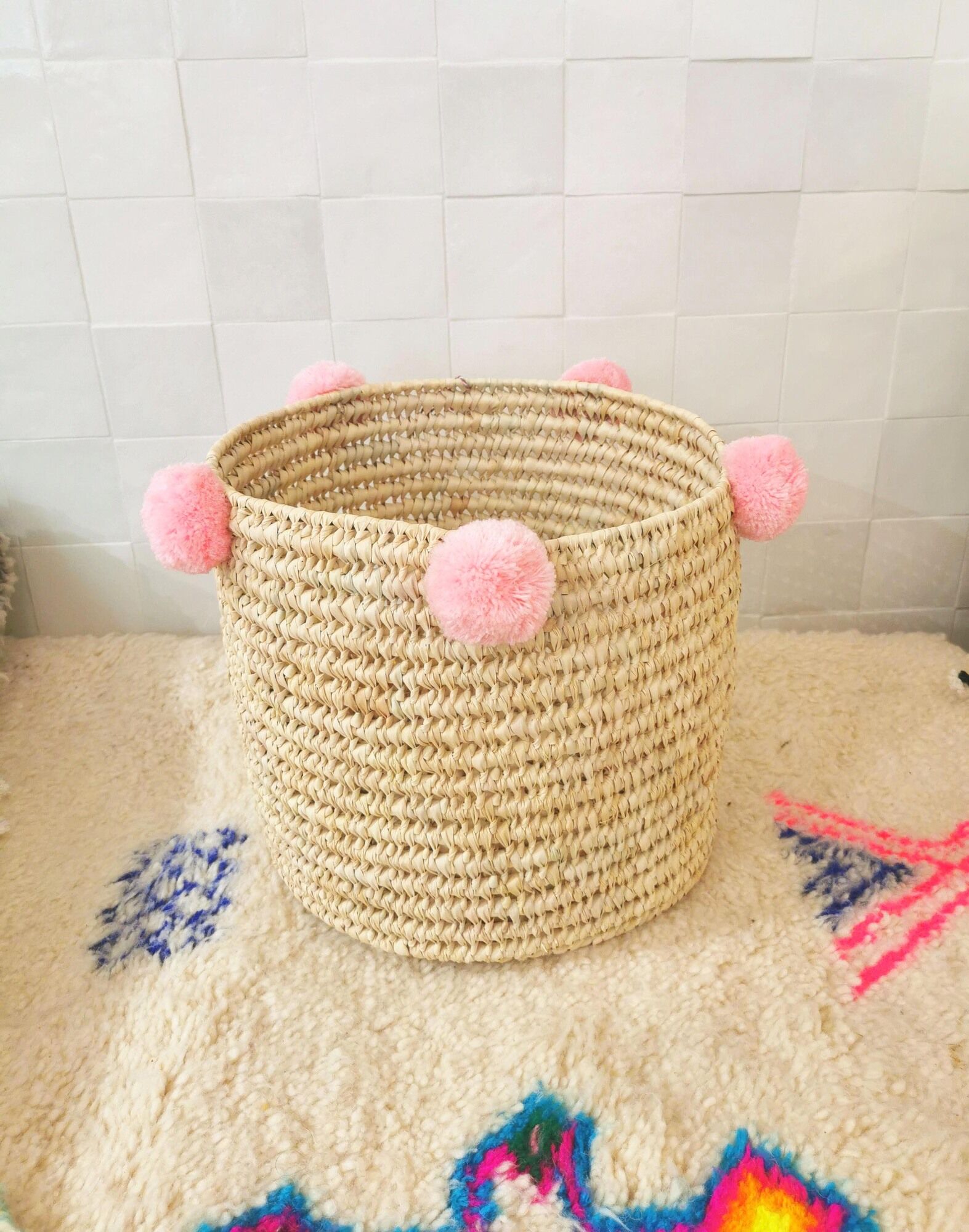 Moroccan basket with pale pink pompoms made of palm fiber
