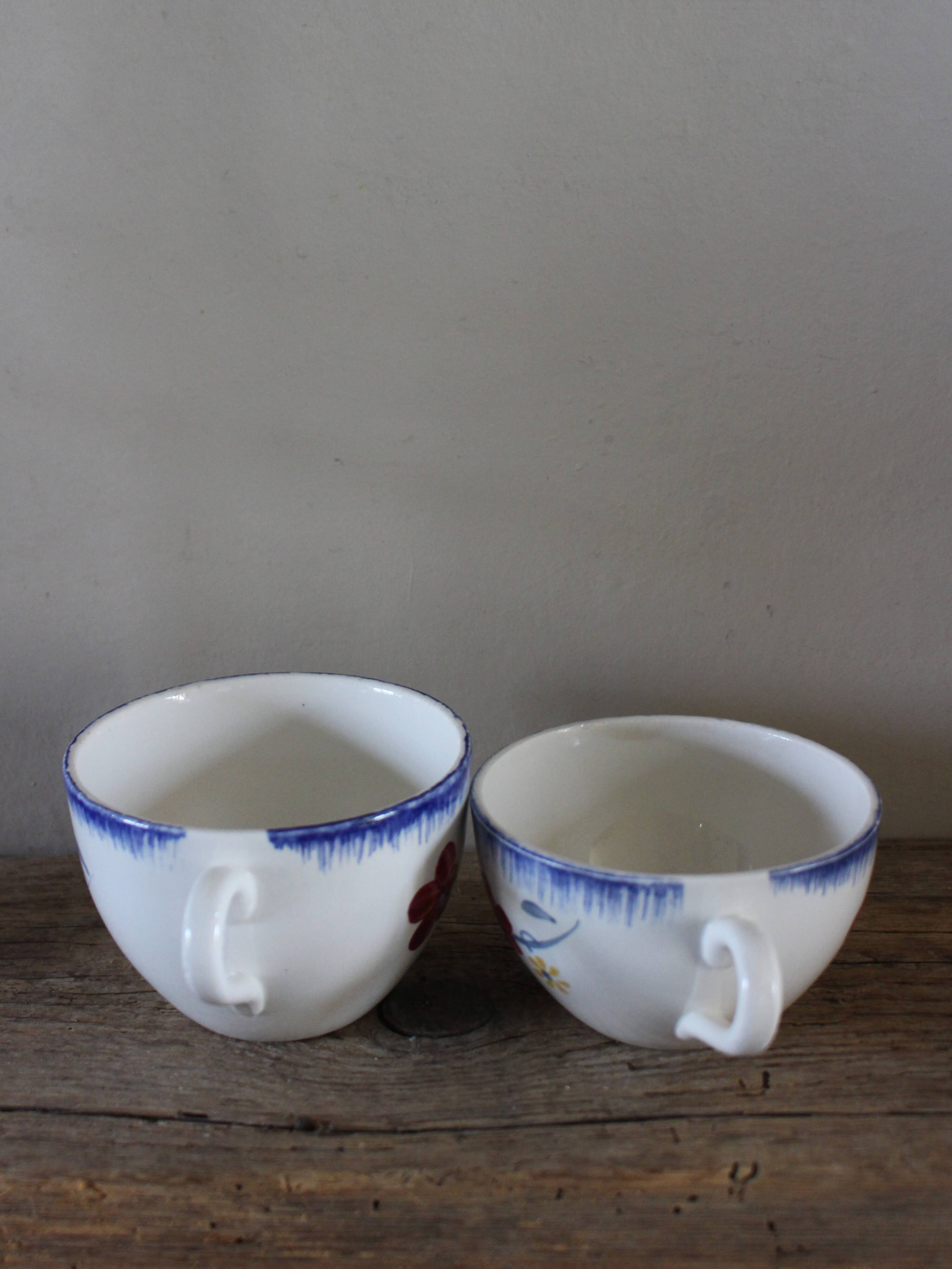 A set of two Digoin earthenware cups with blue, red, and yellow flowers.