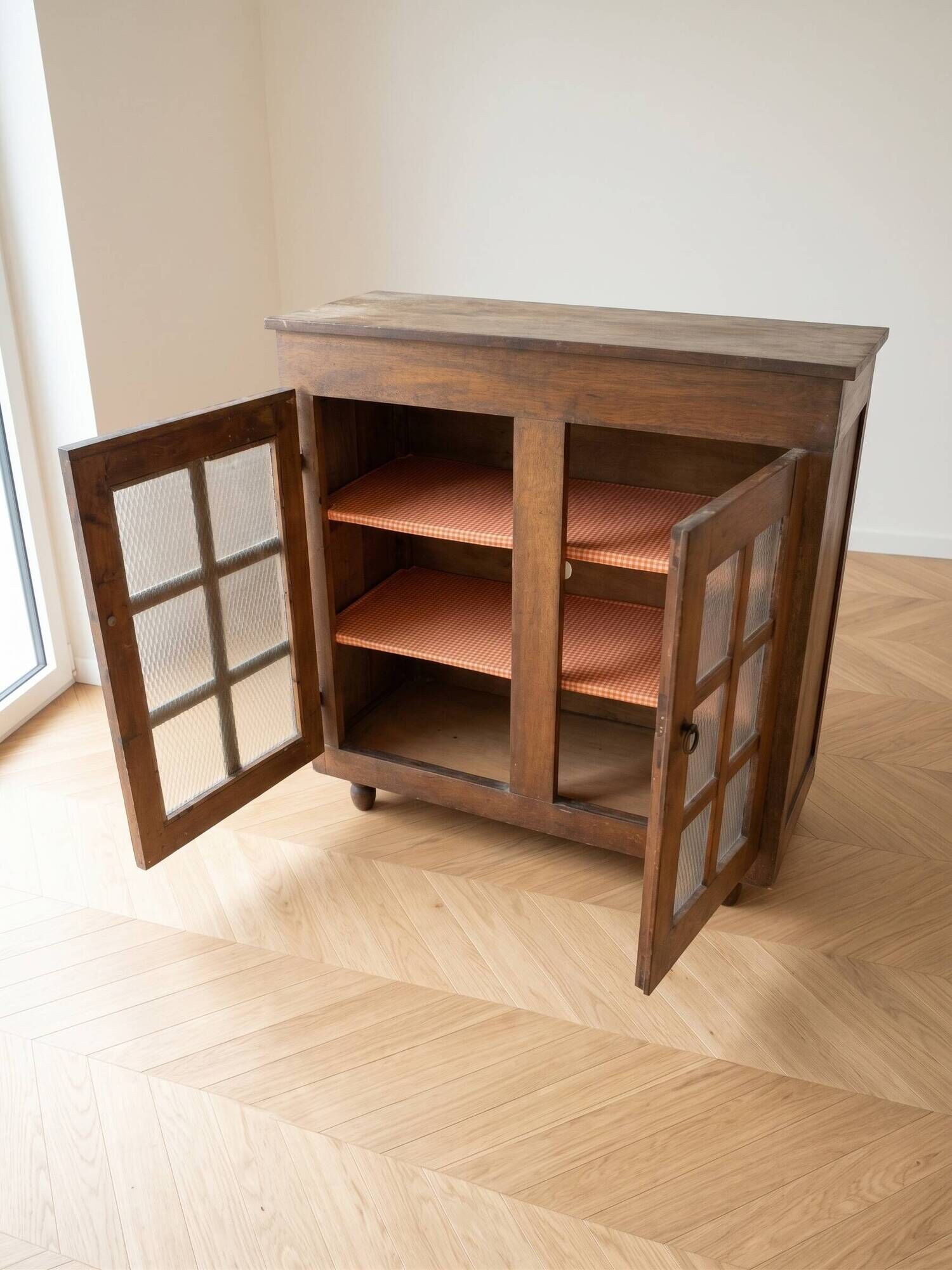 Small antique wooden sideboard with glass doors.