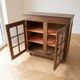 Small antique wooden sideboard with glass doors.