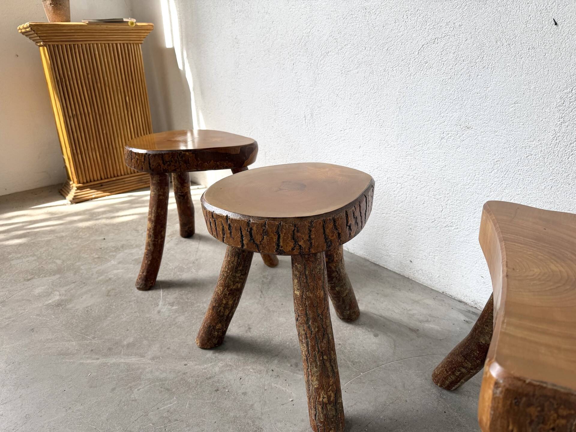 Set of three rustic solid wood tripod stools.
