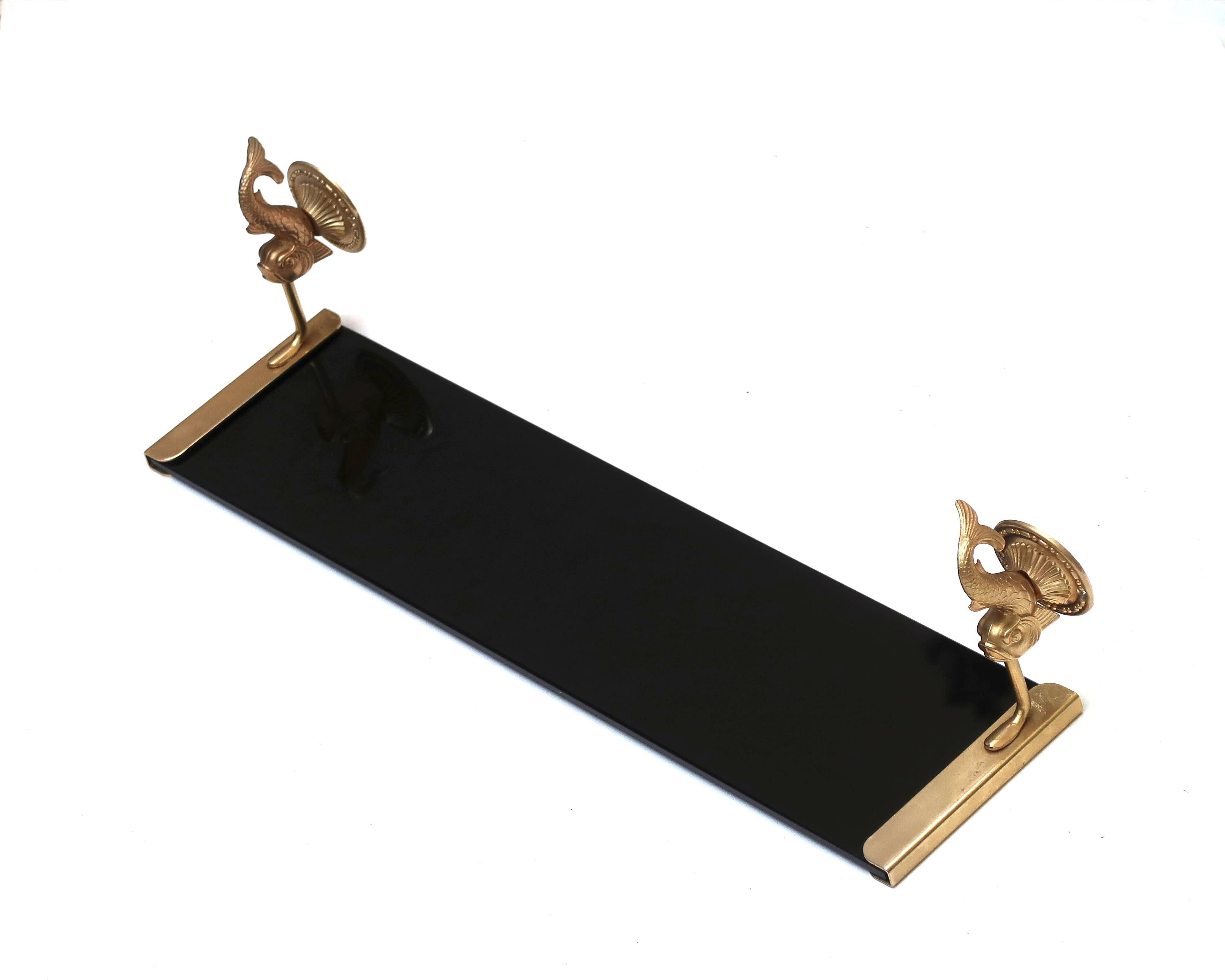 Wall shelf in gold metal and black glass adorned with fish.