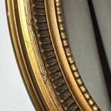 Oval-shaped wooden mirror in gold color