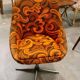Vintage space age swivel chair with psychedelic pattern in shades of orange.
