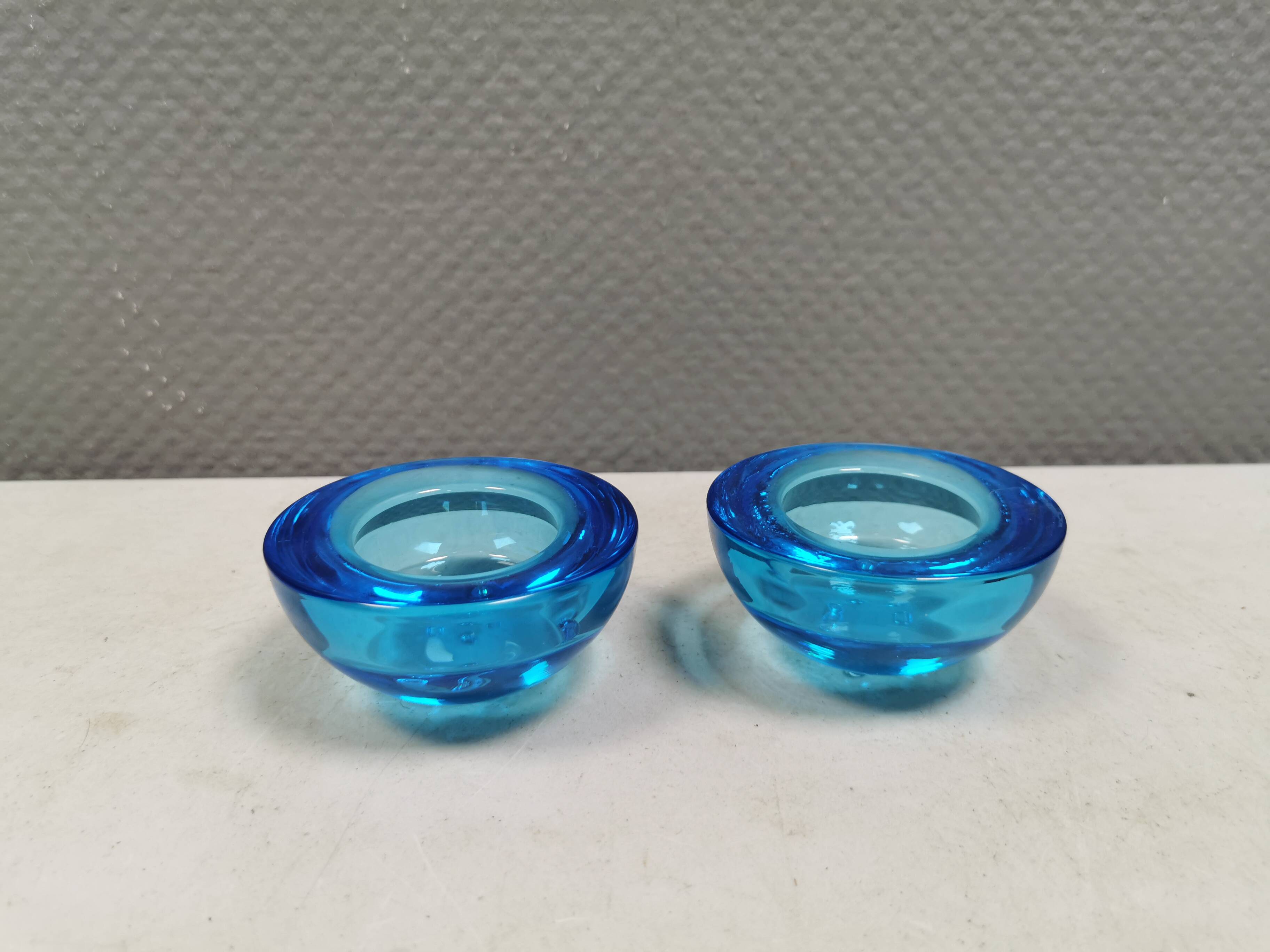 A set of iitalla candle holders in blue transparent glass.