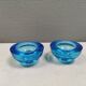 A set of iitalla candle holders in blue transparent glass.