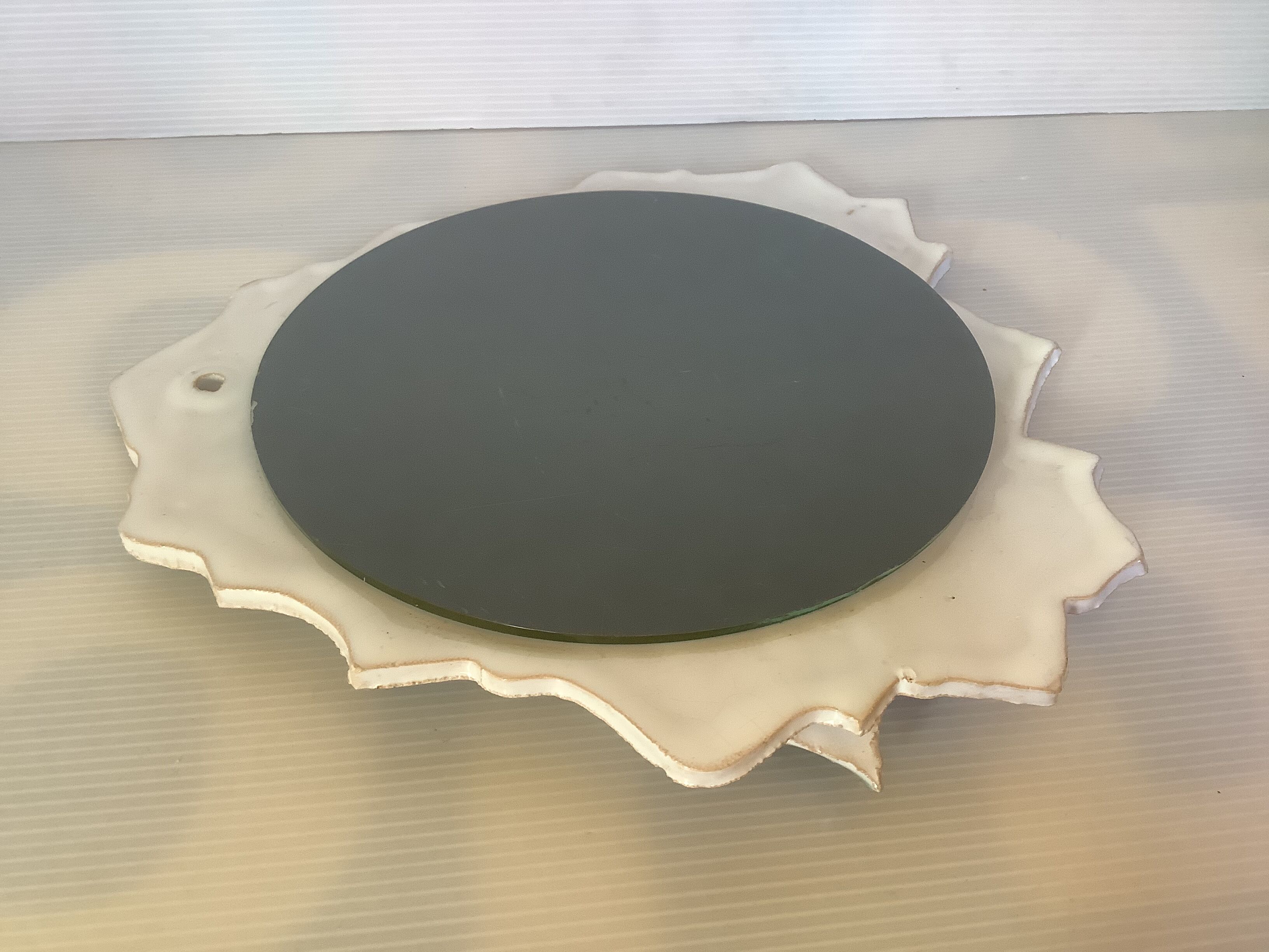 Ceramic mirror with serrated edge and a flower