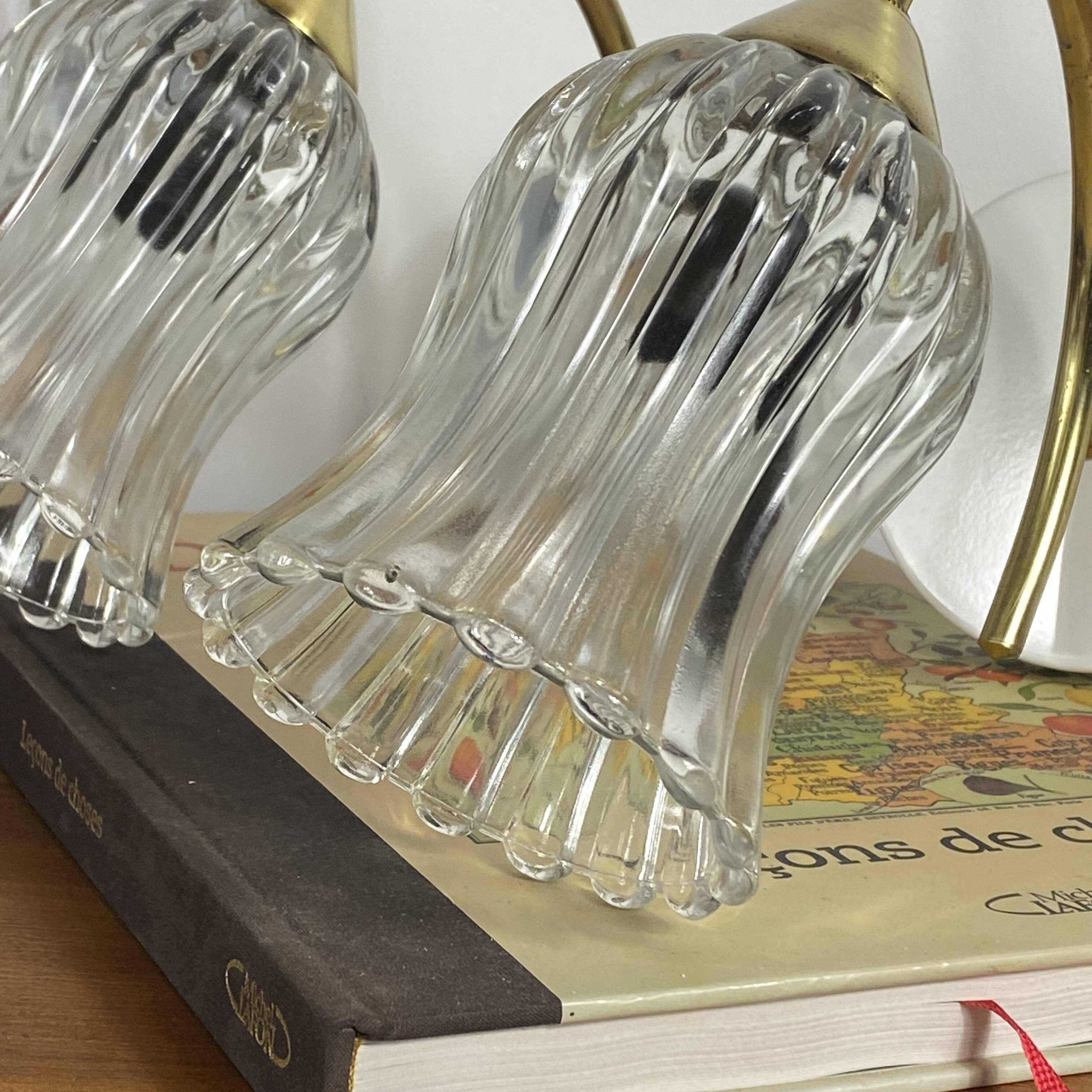 Pair of wall sconces in brass with transparent tulip glass shade.