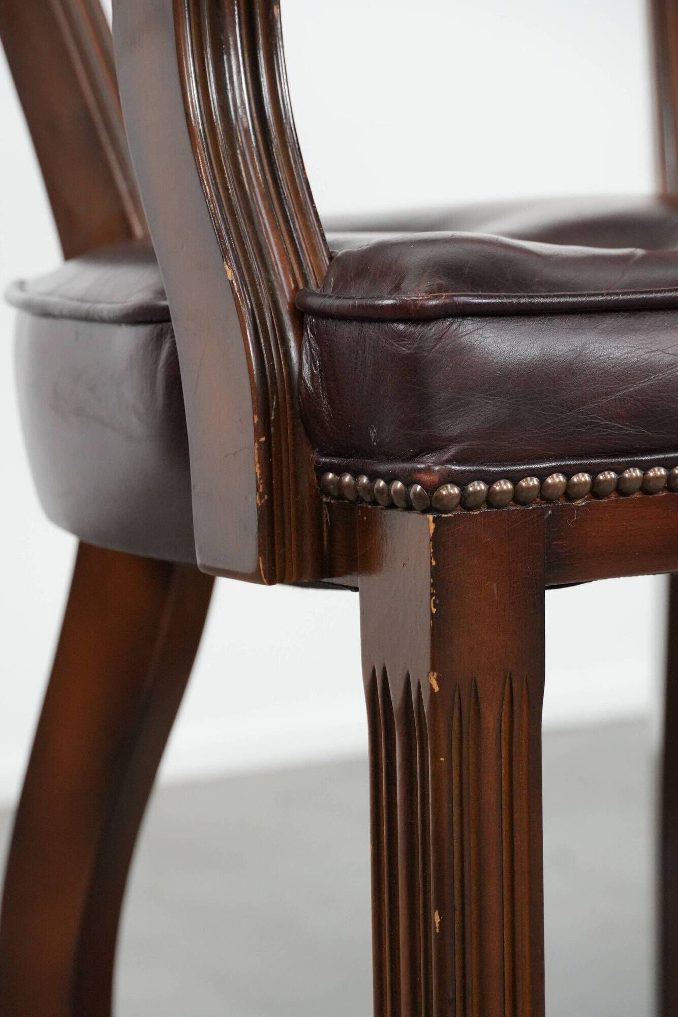 Set of two brown leather Chesterfield dining chairs in English style.