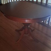 Round solid walnut table with central leg from the 1950s with extensions.