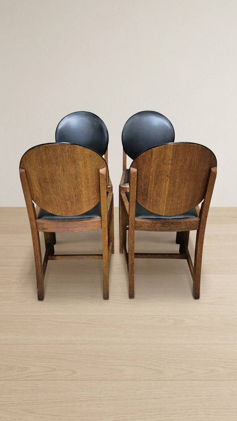 Set of four vintage wooden dining chairs with black leather upholstery