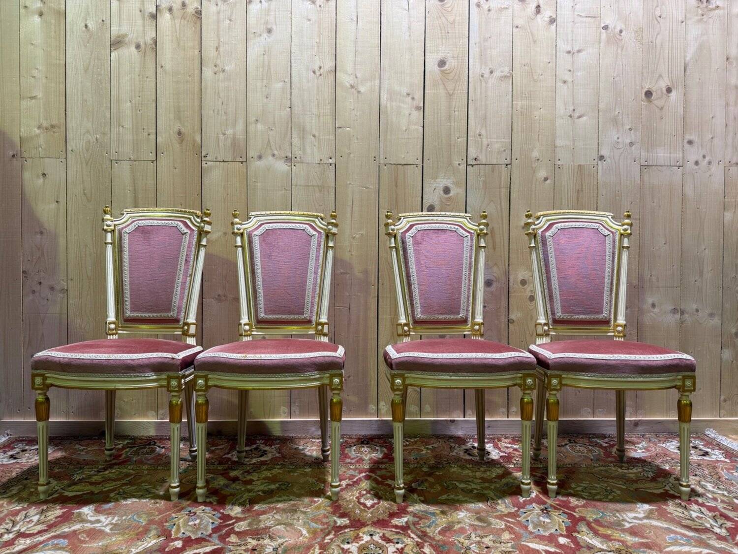 Louis XVI dining room table set with painted wood, gold accents, and pink velvet.