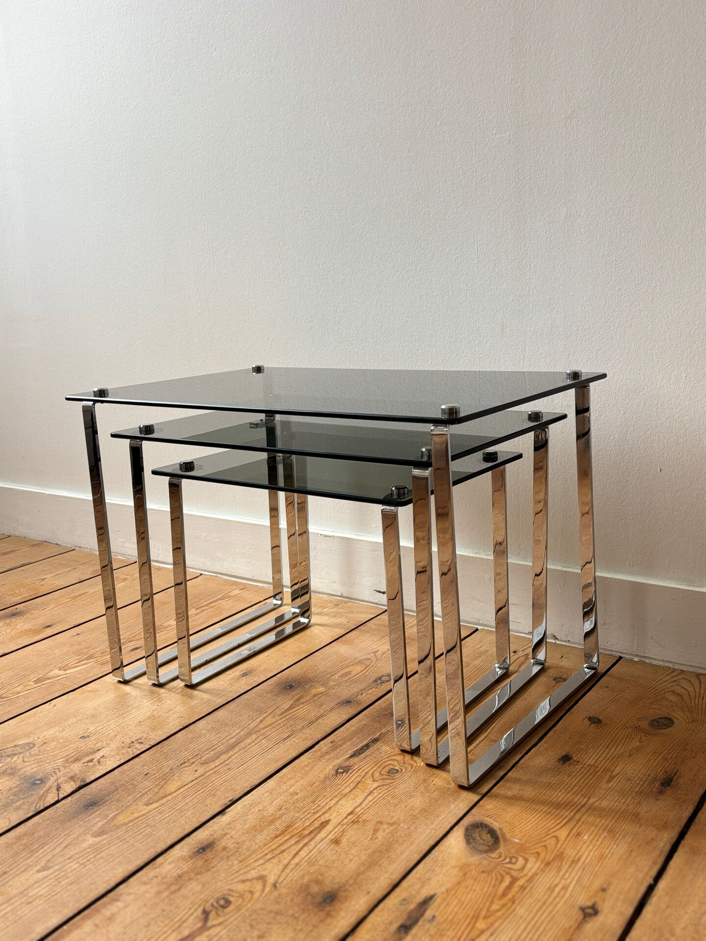 Nest of coffee tables in chrome with smoked glass top.