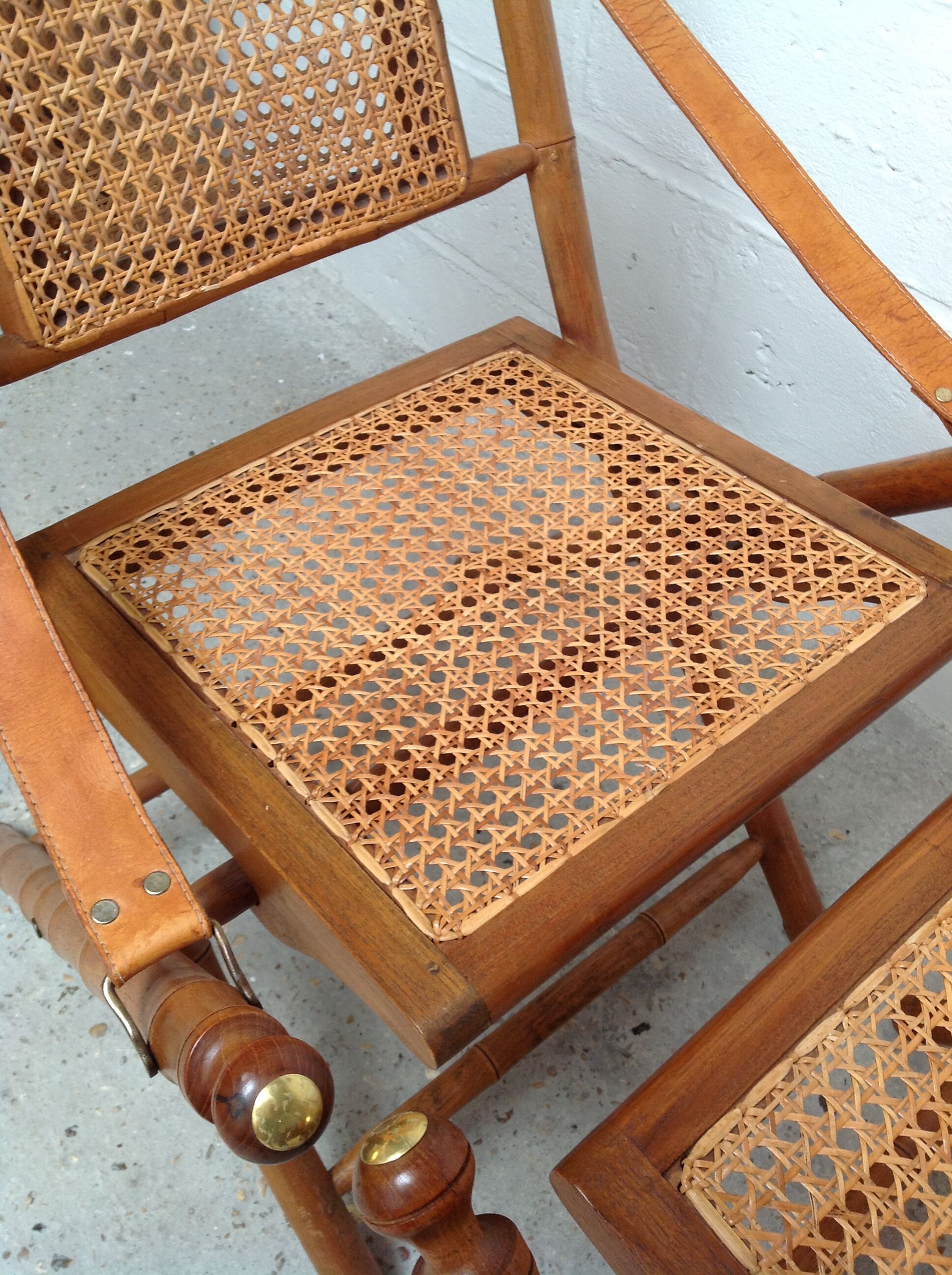 Pair of folding chairs in bamboo and caning, leather and brass