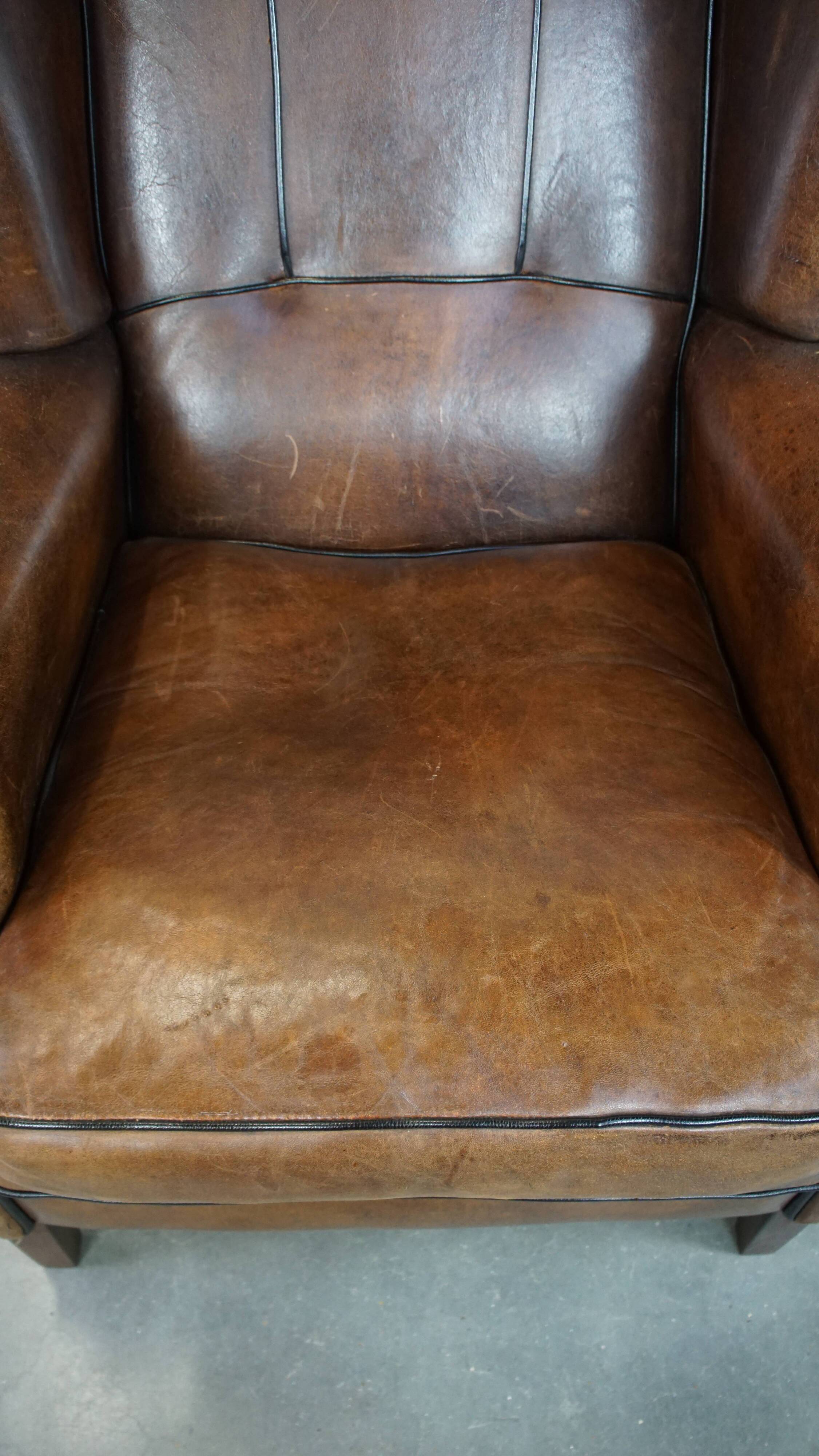 Vintage sheepskin wingback chair finished with black piping