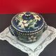 Small covered terracotta pot enamelled savoie or alsace flowers on a blue background