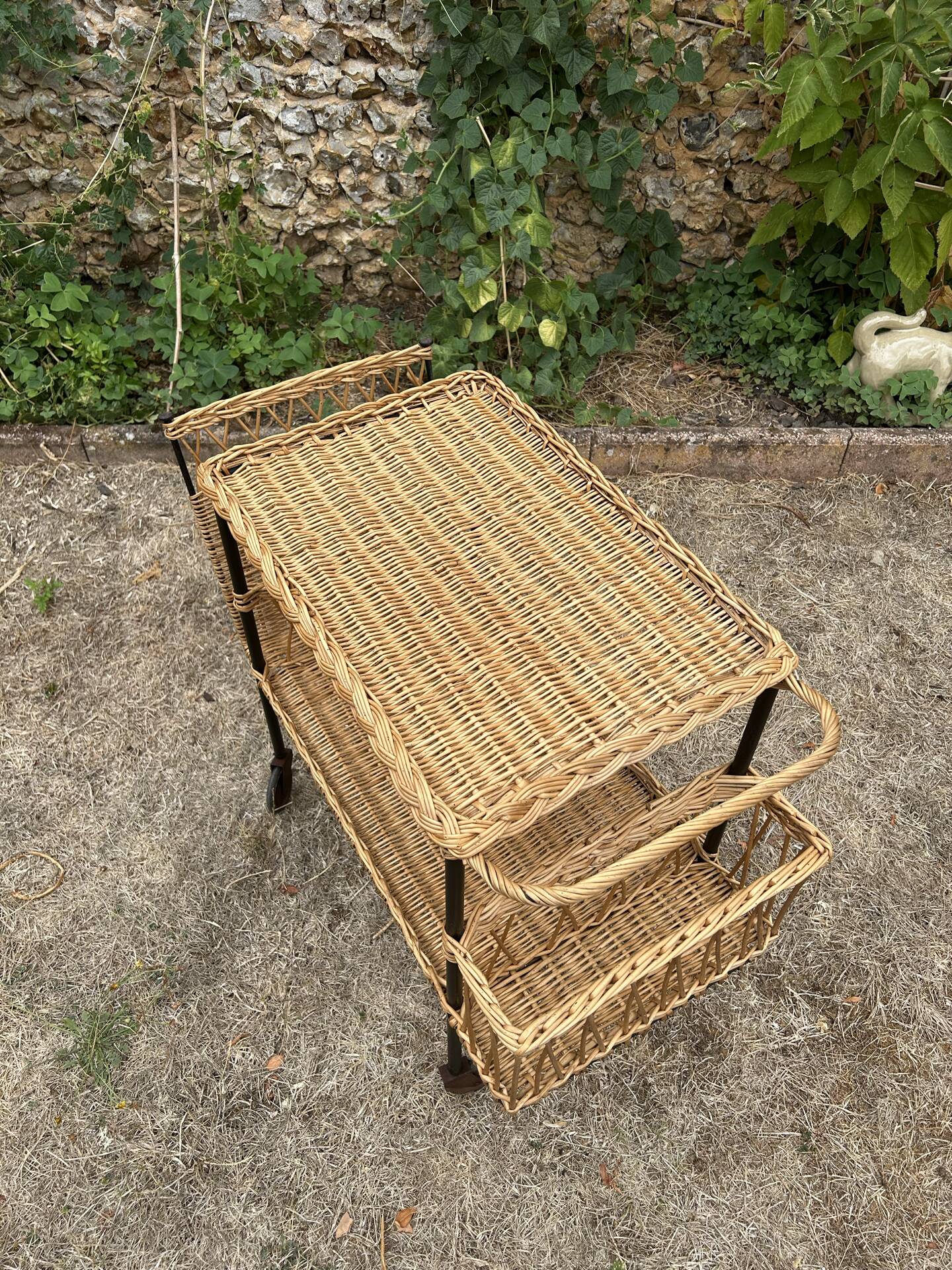 Vintage 1950s rolling dessert trolley in wicker and black tubing.