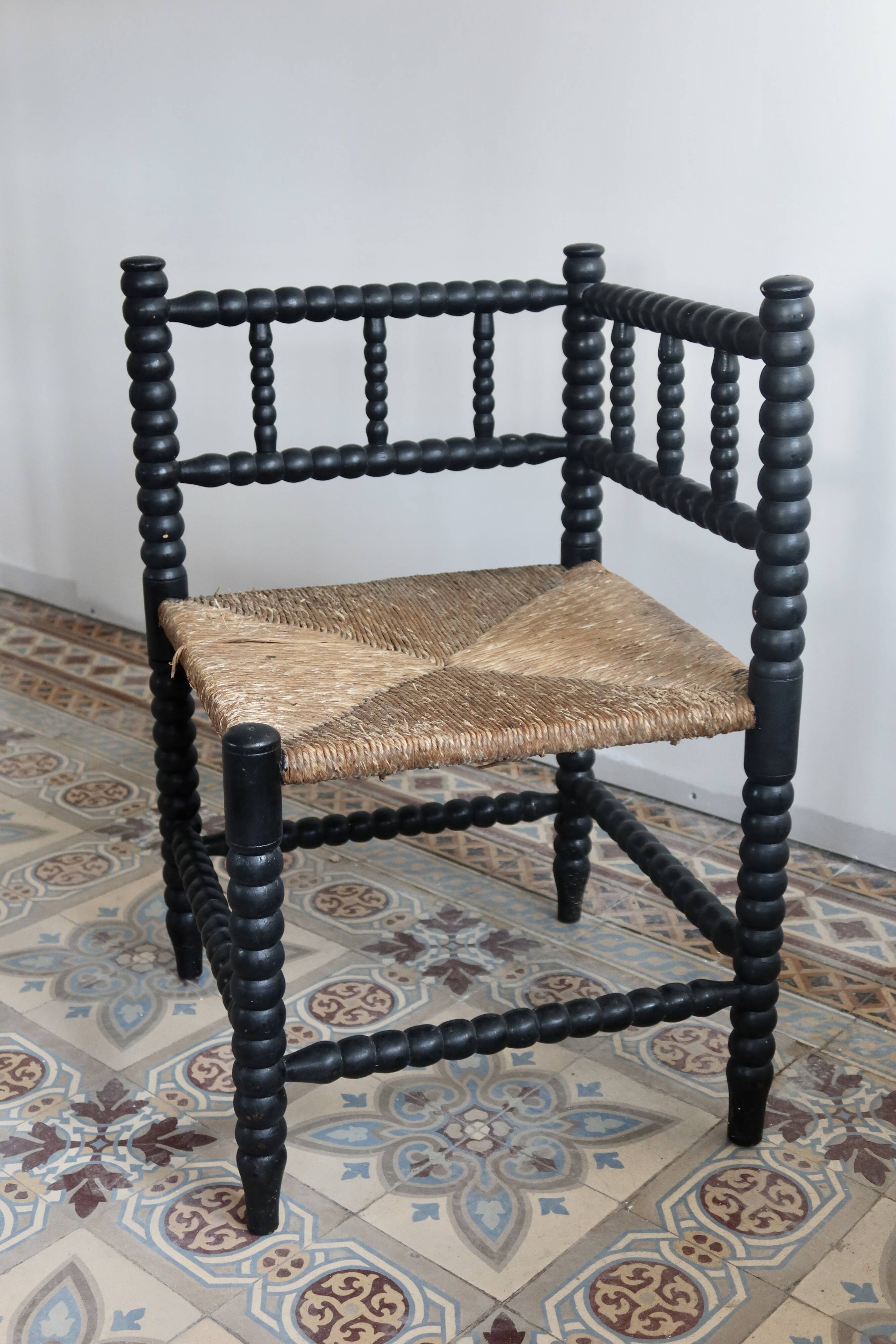 Antique black turned wood corner chair with a straw seat.