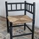 Antique black turned wood corner chair with a straw seat.