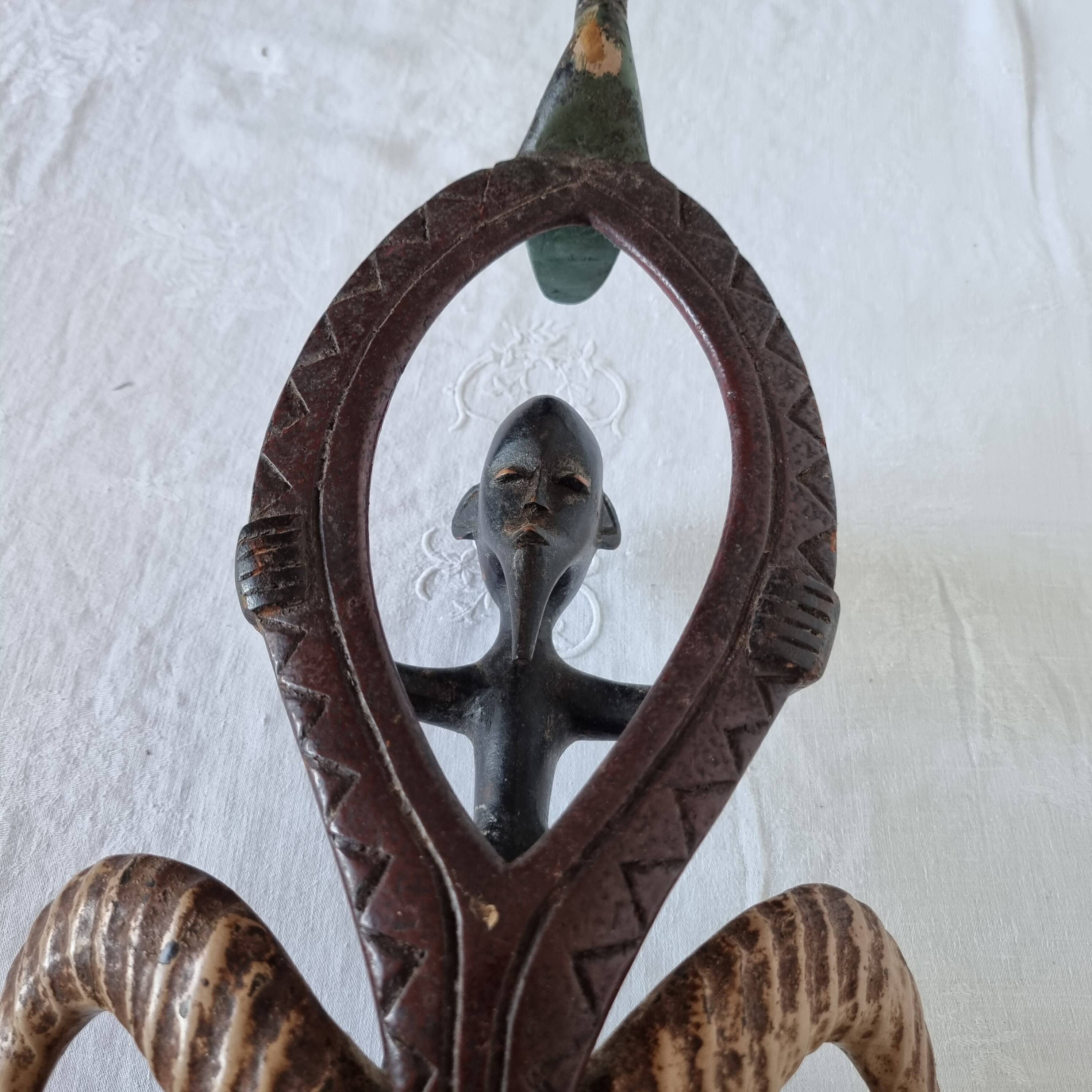 A large Senufo mask made of colored wood, decorated with an anthropomorphic figure