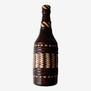 Glass bottle covered in brown leather and cream-colored wicker