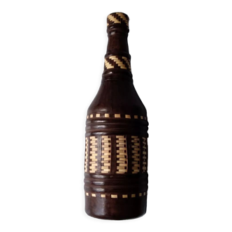 Glass bottle covered in brown leather and cream-colored wicker