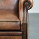Sheepskin wingback armchair with decorative nails and black piping