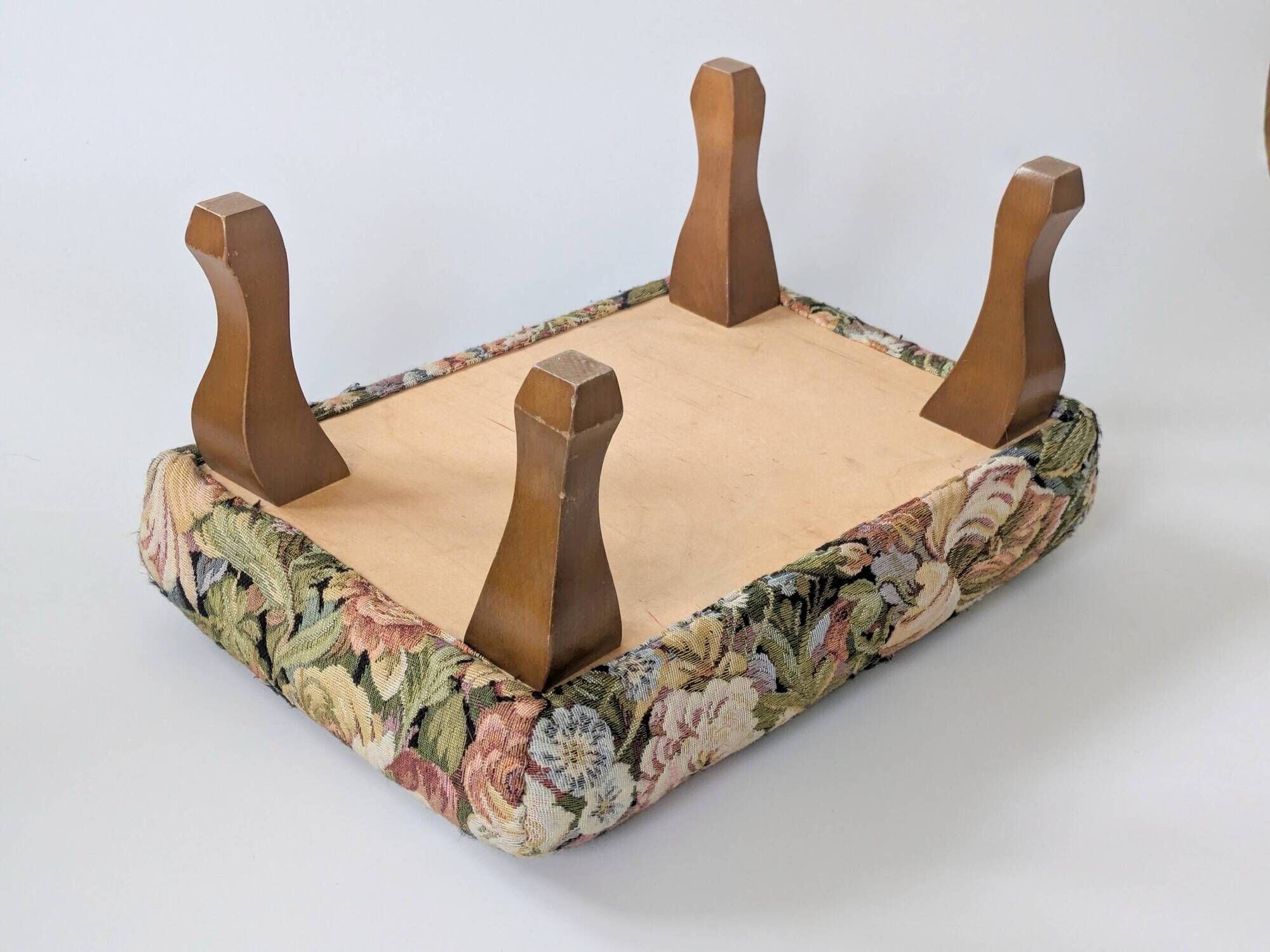Large vintage upholstered footstool with curved legs.
