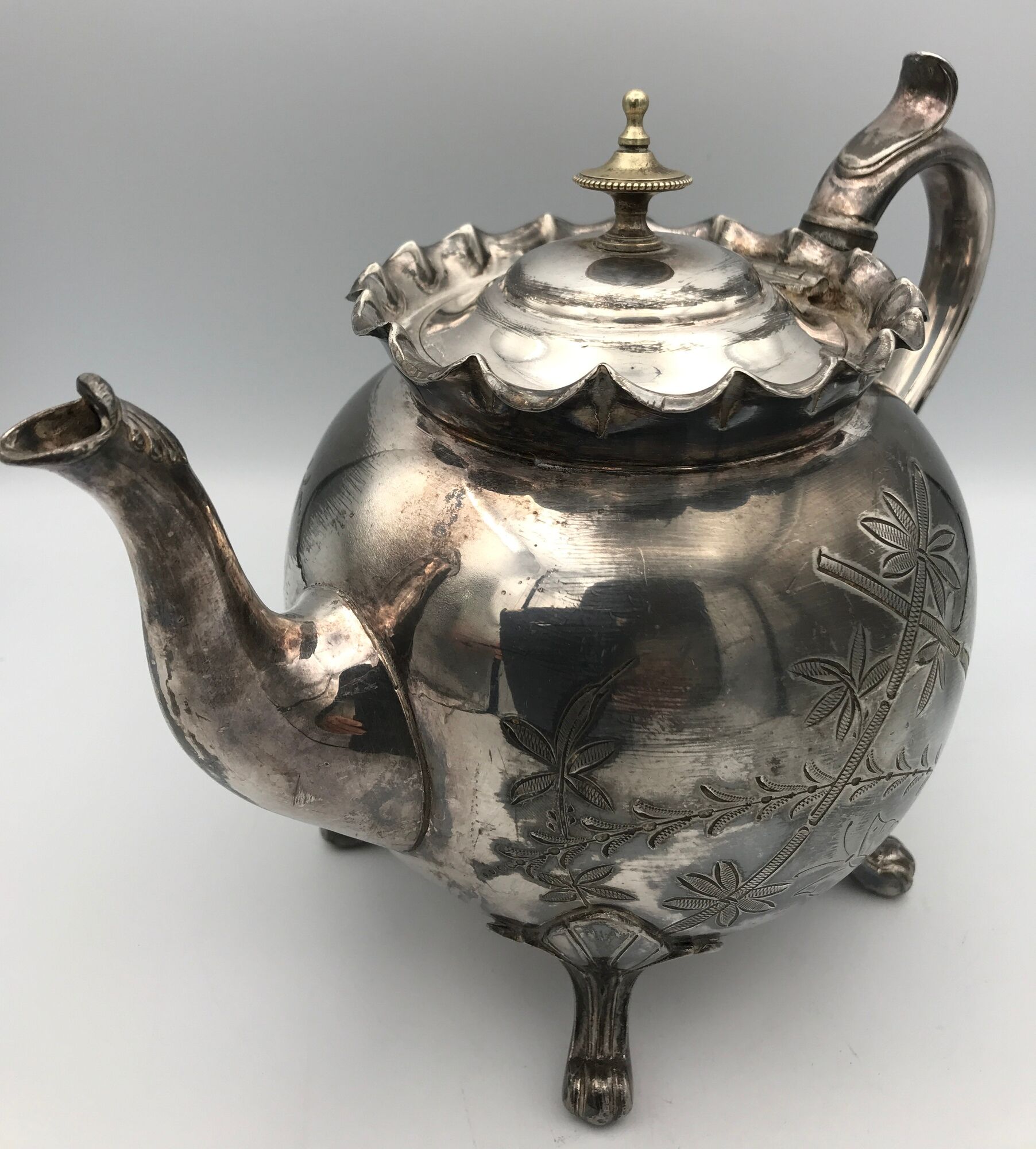 Old teapot pourer in silver metal decorated with foliage and butterflies