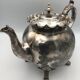 Old teapot pourer in silver metal decorated with foliage and butterflies