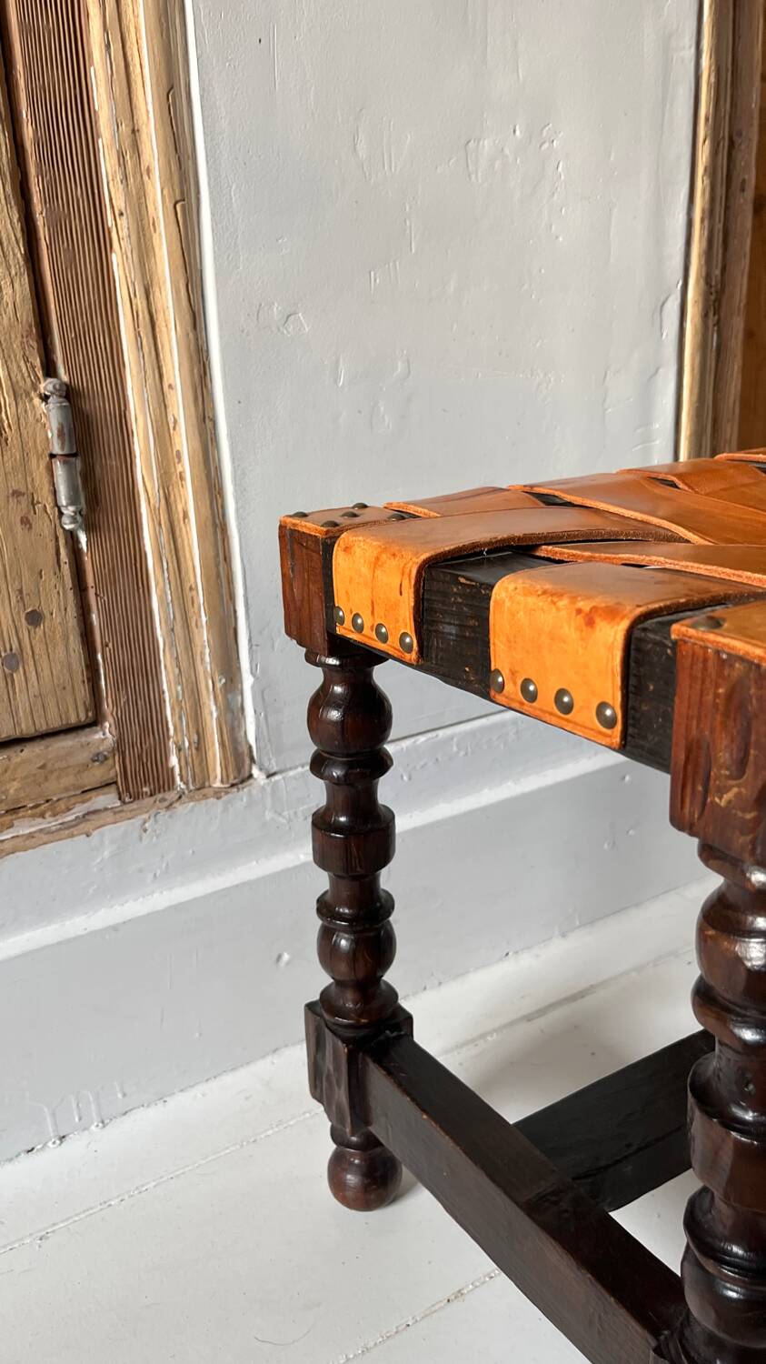 Antique turned wooden stool with woven leather.