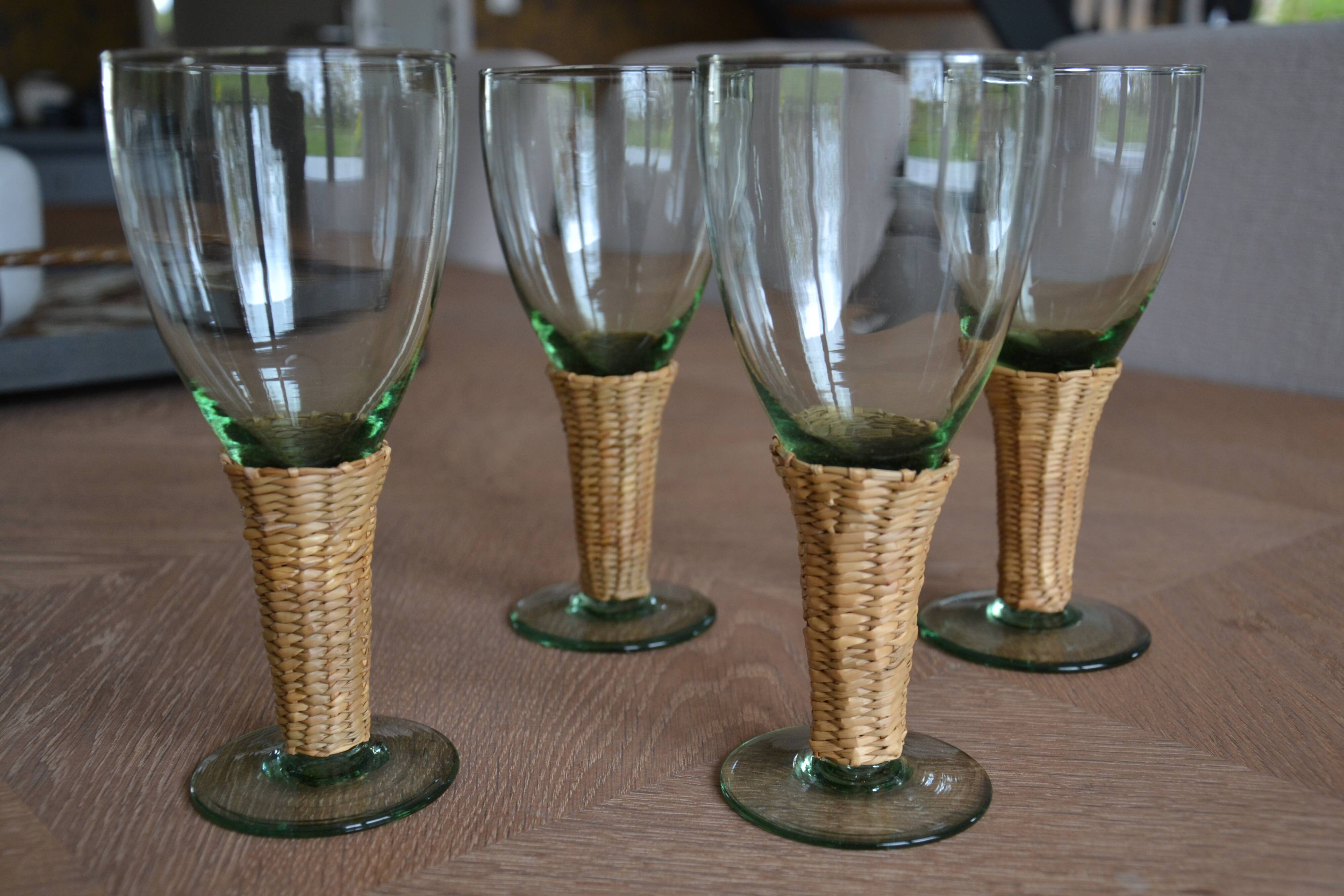 Four stemmed glasses surrounded by rattan.